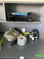 Shelving with medicine ball, massage tools, hand weights, beige cloth, scissors, a holder rack with notebooks, and a green pen