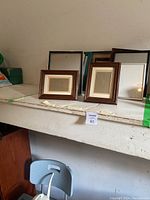 Overview image showing seven assorted picture frames arranged on a shelf, with two small wood frames front and center.