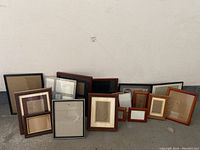 Photo showing the full assortment of 17 picture frames in wood, black, and reddish brown finishes in various sizes arranged on the floor.