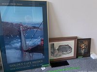 Framed Golden Gate Bridge 50th anniversary poster with blue and black border, showing the bridge from an aerial angle.