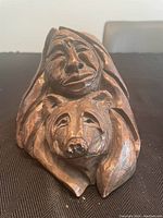 Front view of the wooden carving showing a stylized human face and a bear's head.