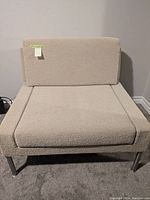 Front view of the modular chair showing light beige wool upholstery and removable seat cushion with chrome legs.