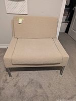 Front-facing view of the modular style chair showing the light beige wool upholstery and removable cushions with chrome legs.