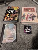 Lot items arranged on floor: two Bibles, travel journal, small notepad, cross necklace with pendant, extra cross pendant on card.