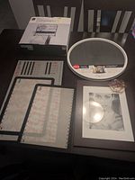 Photo showing entire lot including boxed over-the-door organizer, non-skid turntable, baking mats, floral resin coaster, and picture frame with mat and sample photo