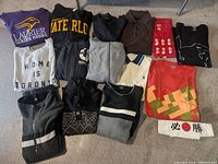 Overview of multiple sweaters and tops laid out on the floor showing variety of colors and styles