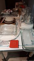 View of all items on table including Pyrex baking dishes in foreground, several plates behind, white Cuisinart food processor on right, small red dish, and cookie molds in plastic below dishes.