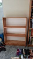 Front view of the wooden bookshelf showing three shelves with natural wood grain finish.