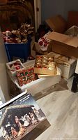 Overview of Christmas decor items including boxes with ornaments, poinsettia floral stems, and bags.
