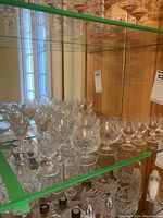 Crystal brandy snifters and liqueur glasses on glass shelving, showing detailed cut-glass patterns and shapes.