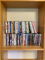 Full shelf of DVDs showing assorted movie titles including Magnolia, Lord of the Rings, and Jurassic Park, plus more.