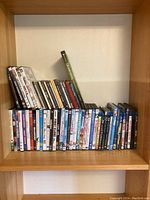 Shelf of DVDs and CDs including movies and music with various titles arranged horizontally.