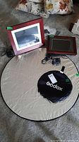 Two wood-tone framed digital photo frames, one HP model DF1200A1-16 with power cord, one smaller Memory Frame MF-1040, plus a round silver reflector mat and black Godox carry case for reflector.
