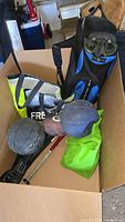 Box with assorted sporting equipment including balls, boxing gloves, dive mask, skipping rope, and bat.