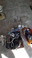 Photo showing multiple wrenches, mechanical timers, headphones, and electrical cords scattered on carpet.