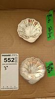 Two Birks sterling silver scallop shell dishes displayed on a cardboard surface with measurement tag indicating 3 inches size.