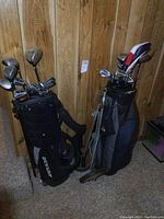 Two sets of men's right-handed Dunlop golf clubs in bags, positioned against a wood-paneled wall.