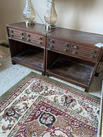 Two Kaufman wood night tables side by side, showing front and top, with brass hardware and lower shelf. Tables show wear and some dust.