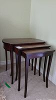 Three wood nesting tables stacked, dark finish, slender legs