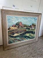 Full view of the framed painting leaning against a door, showing the farm scene with barn and fencing.