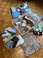 Photo of plastic tote, woven basket, assorted fabric pieces, sewing patterns, and tools displayed on wooden floor