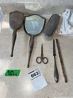 Vanity set items including hair brush, mirror, clothes brush, scissors, nail file, and comb, arranged on countertop with cloth bags.