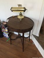 Full view of wooden oval table with brass desk lamp on top showing carved detail and lamp design.