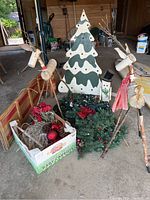 View of the lot showing birch wood deer, wooden toboggan sled, artificial garland, painted Christmas tree cutout, and snowman decoration.