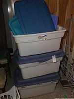 Stack of three large Rubbermaid storage totes with lids, including extra lids visible inside the top tote.