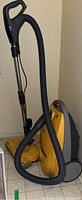 Side view of yellow Kenmore Elegance vacuum with hose and carry handle visible