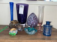 Full view of the lot showing various glass vases, bottles, and paperweights in different colors and shapes.