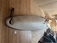 Top side view of the white Bic 151 windsurf board showing rounded nose and attached bungee cords.