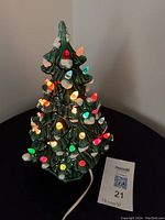 Lit ceramic Christmas tree showing multiple colored bulbs illuminated.