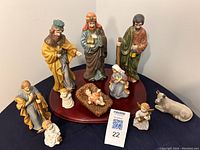 Full set of 10 ceramic nativity scene figures including the Wise Men, angels, Mary, Joseph, baby Jesus, cow, and wooden base displayed on a flat surface.