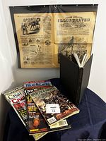 Full view of magazines, hardcover book, and vintage newspaper page display.