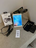 Full view of iPad Mini, Samsung 3D glasses, phone cases laid out on surface