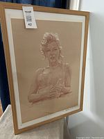 Framed chalk drawing print of Marilyn Monroe shown upright against a wall. Frame is wooden with no glass. Size approximately 29x27 inches.