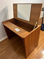 Front angle of wooden MCM vanity desk showing open hinged top with mirror and storage compartment.