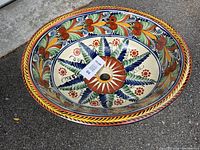 Top view of the oval ceramic sink basin showing the colorful floral mosaic pattern centered around the drain hole.