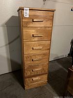 Front view of the tall wooden dresser showing six drawers and handles.
