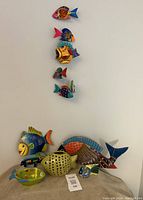 Full view of six fish decor pieces arranged vertically and horizontally on wall and surface.
