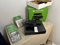 Xbox One console, Kinect sensor and games displayed on fabric surface