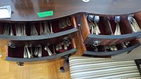 Two wooden drawers lined with red velvet containing multiple compartments of silver flatware