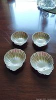 Four shell-shaped sterling silver dishes arranged on table.