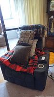 Full view of couch with multiple throw pillows and wool blankets, showing red checkered blanket and pillow arrangement.