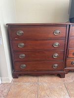 Front view of vintage wooden dresser showing four drawers with oval metal handles and base details