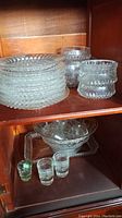 Stack of clear pressed glass plates and grouped punch bowls with starburst patterns