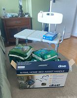 The lot overview showing the shower chair, disposable underwear packages, bed assist handle box, and Vicks vaporizer on top of the chair.