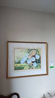 Framed watercolour floral painting with gold frame hung on wall, showing the full artwork and frame.