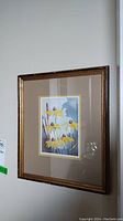 Framed watercolor painting hanging on a wall, showing scratches on the frame surface.